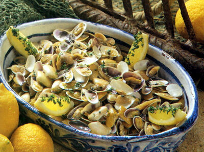 Er staat een blauw-witte schaal vol met zeevruchten, citroenen en kruiden.