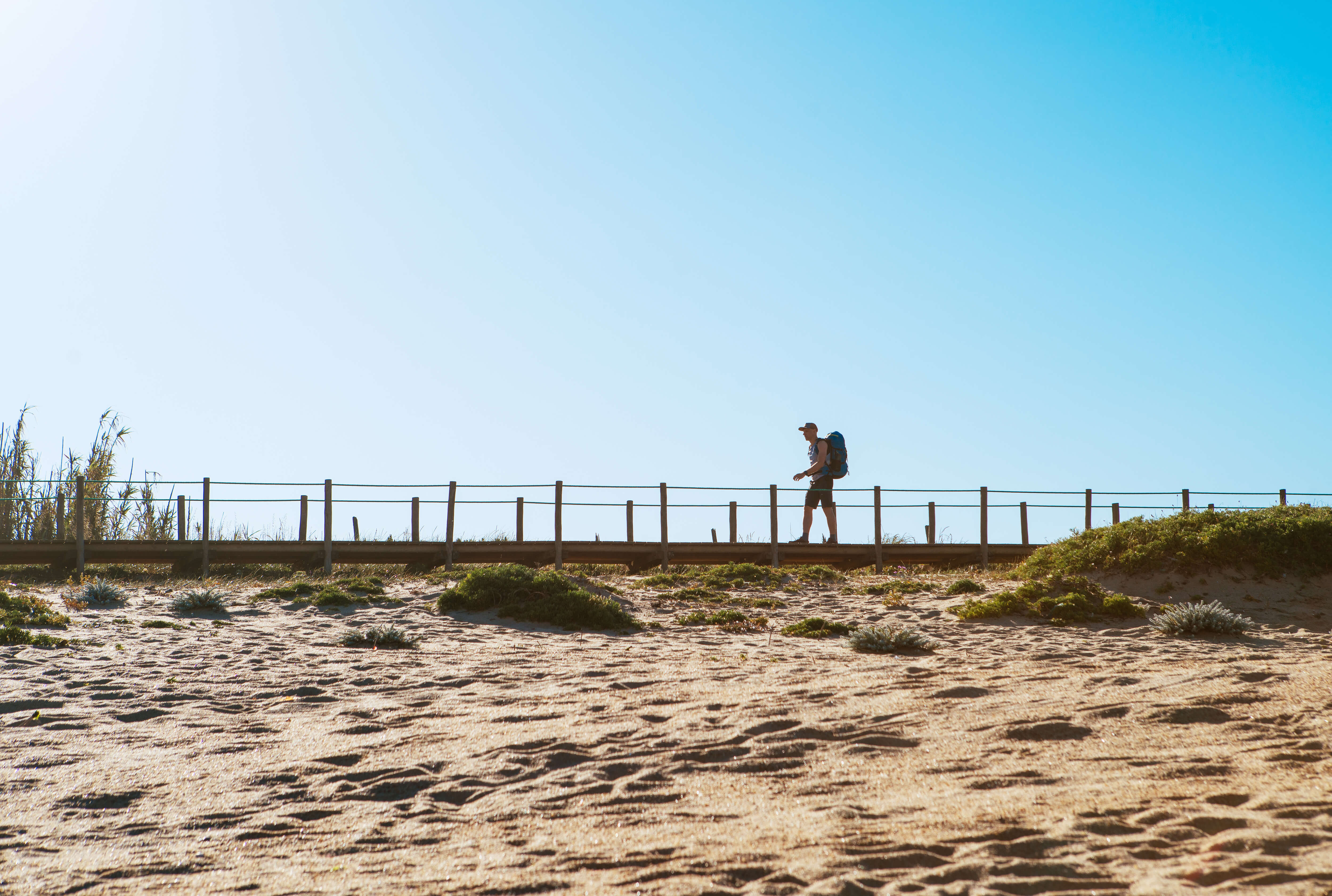 A hillwalker passing by a sandy beach in the morning on the Camino Portuguese 