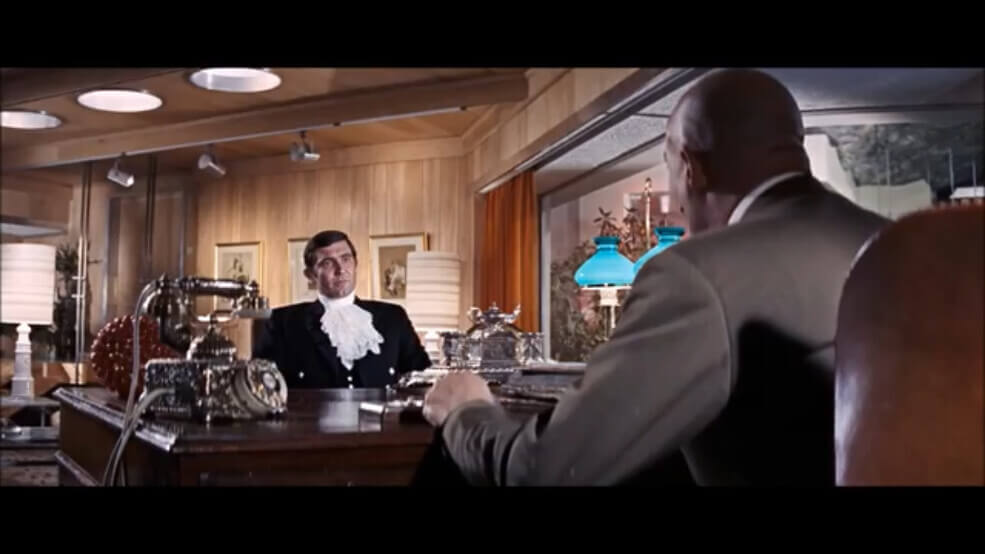 Screen grab from on her majesty's secret service (1969) James Bond sits at adesk across from Ernst Stavro Blofeld