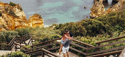 couple embracing on a wooden boardwalk overlooking cliffs and the ocean in algarve portugal showcasing love and travel. 7876593 scaled