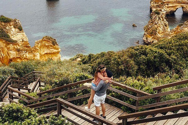 couple embracing on a wooden boardwalk overlooking cliffs and the ocean in algarve portugal showcasing love and travel. 7876593 scaled