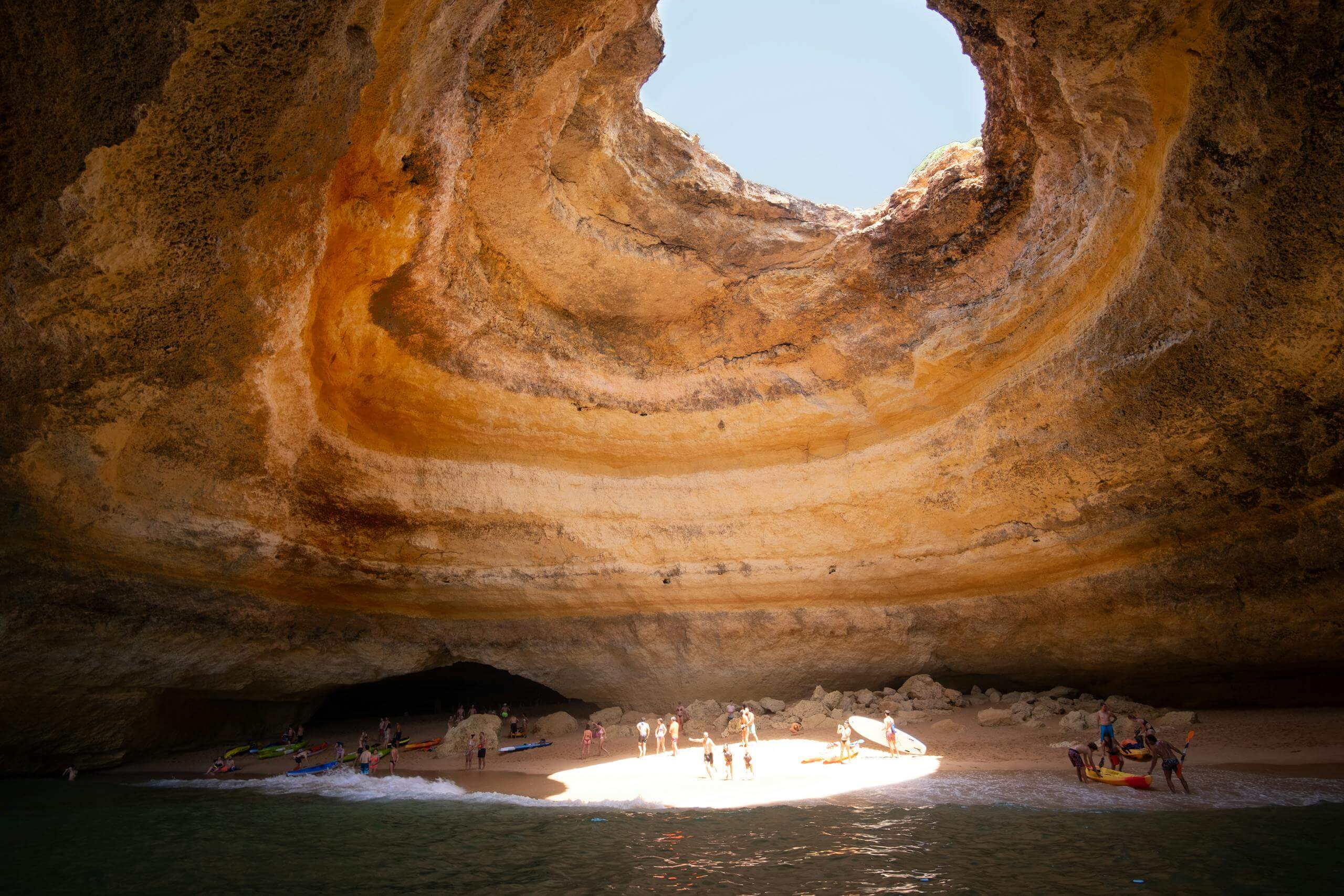 Stunning view of the Benagil sea cave with sunlight illuminating the sandy beach.