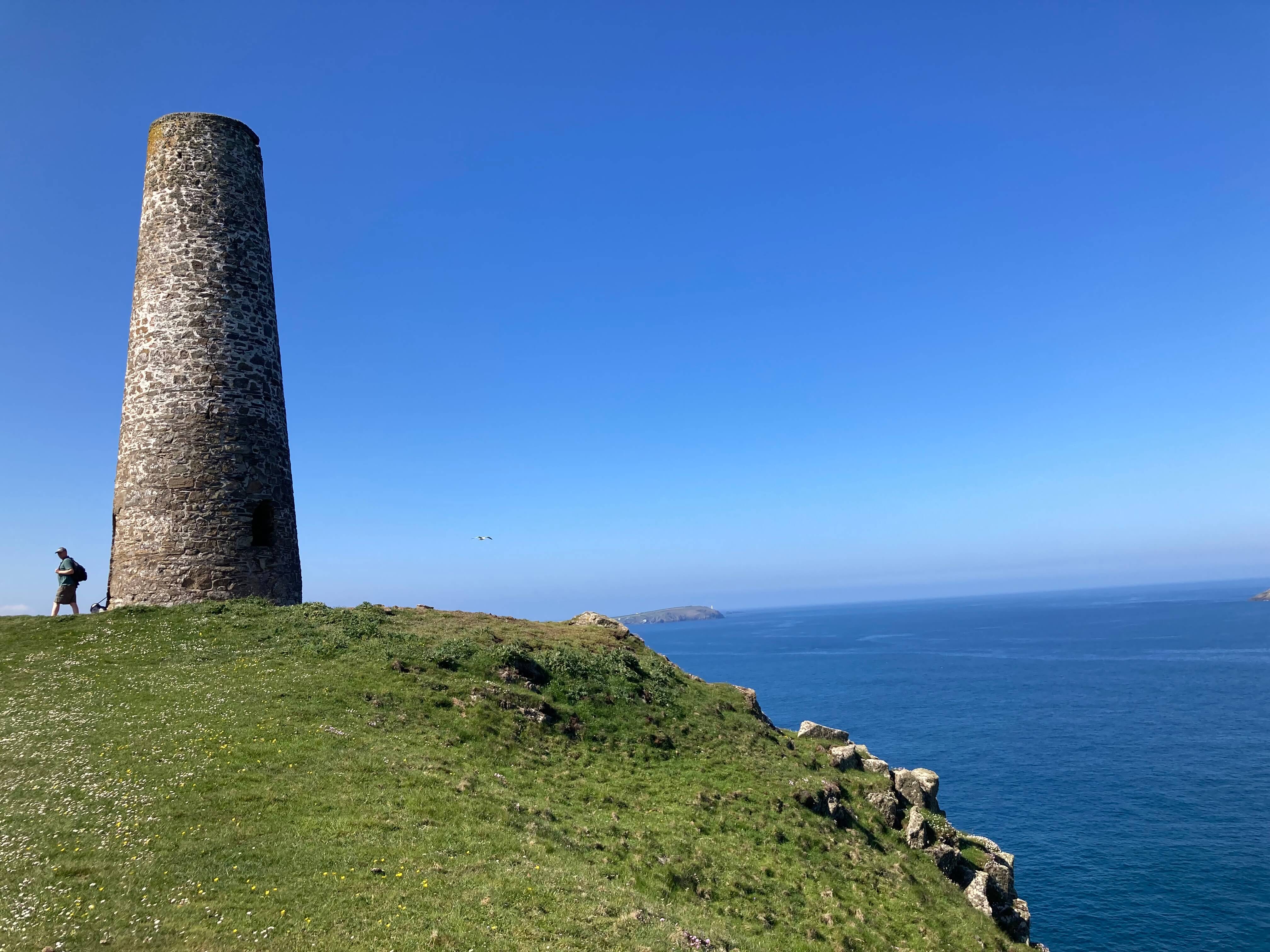 swcp71213 alessandra silauri hiker by clifftop tower blue sea beyond img 9994